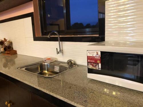 a kitchen counter with a sink and a microwave at Luzville Residences - C8 in Naic