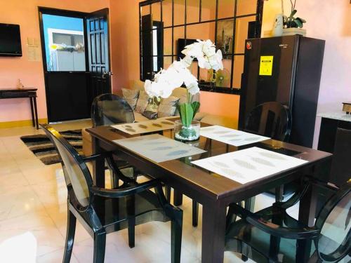 a dining room table with a vase of flowers on it at Luzville Residences - C8 in Naic