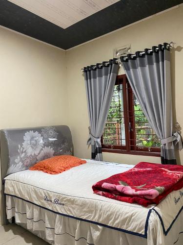 1 dormitorio con 1 cama con cortinas y ventana en Paima Homestay, en Laguboti
