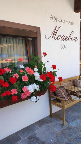 a window box filled with red and white flowers next to a bench at Appartement Moaeben in Alpbach