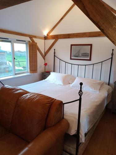um quarto com uma cama e um sofá em 4 Kingsize Beds Ensuite - Sleeps 8-10 - Rural Contemporary Oak Framed House em Chiddingfold