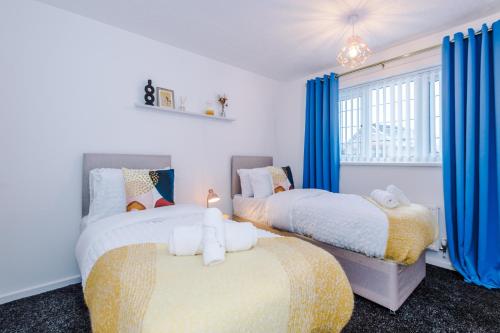2 Betten in einem Schlafzimmer mit blauen Vorhängen und einem Fenster in der Unterkunft West Midlands 3 Bed! Sleeps 5! Perfect for Contractors and Groups! FREE OFF STREET PARKING! 2 Bathrooms! FREE WIFI! Ideal for Long Stays in Ocker Hill