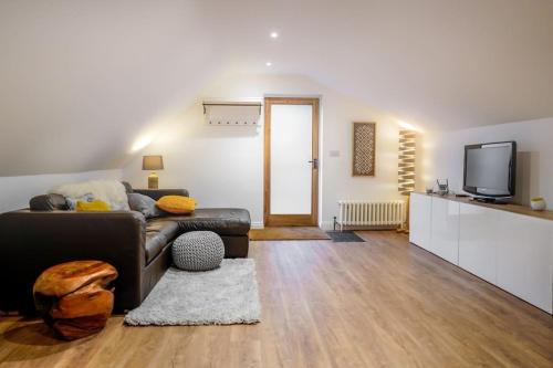 - un salon avec un canapé et une télévision dans l'établissement The Loft Apartment @ Lower Coombe Royal, à Kingsbridge
