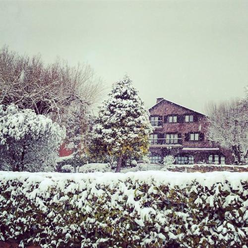 a snow covered yard with a house and a christmas tree at Mas D'en Roqueta in Aravell