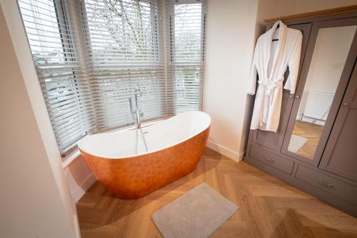 une baignoire dans une salle de bain avec une fenêtre dans l'établissement Luxury Pet-Friendly 2 Bed Retreat in Central Bowness with Copper Roll-Top Bath & Sun Terrace, à Bowness-on-Windermere
