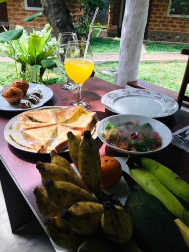a table with plates of food and a glass of orange juice at Sky View Cabin Unawatuna in Unawatuna