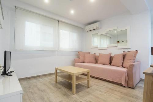 a living room with a pink couch and a table at Apartamento cerca del mar, del puerto y del centro in Valencia