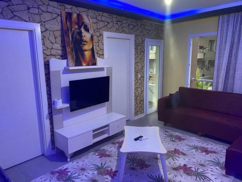 ein Wohnzimmer mit einem TV und einem Sofa in der Unterkunft İmperyum park vilları in Çiftlikköy