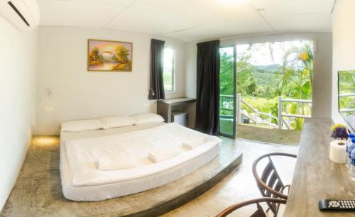 a bedroom with a large white bed and a balcony at Durian Ecolodge in Tampin