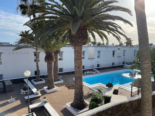 een hotel met palmbomen en een zwembad bij Casa Clara - Playa Matagorda in Puerto del Carmen