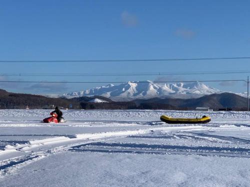 a person sitting in the snow with a canoe at Yadoya YADOKARI in Pippu