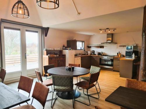 a kitchen with a table and chairs in a room at De Kan Hoeve appartementen in De Veenhoop