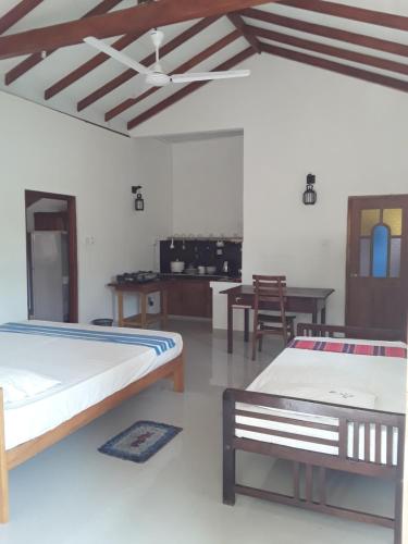 two beds in a room with a table and chairs at The Bamboo Leaf Apartment in Hikkaduwa