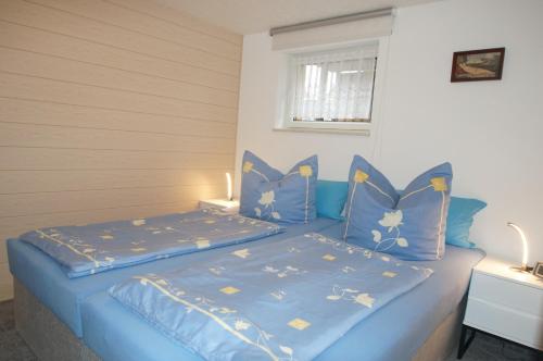 Ferienwohnung Schubert في ساغارد: غرفة نوم بسرير ازرق مع شراشف ووسائد زرقاء