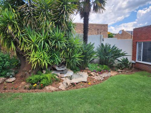 a garden with palm trees and flowers in a yard at SiBella guest house in Bloemfontein