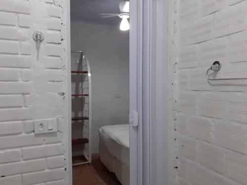 Cette chambre est dotée d'un mur en briques blanches et d'une chambre. dans l'établissement Suíte a duas quadras da Praia e perto da Ilha do Mel, à Pontal do Paraná