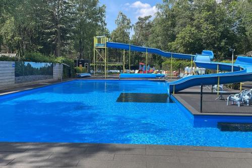 a large swimming pool with a blue water slide at Chalet Toetje op de Veluwe in Hoenderloo