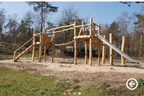 a wooden playground with a slide and a slide at Chalet Toetje op de Veluwe in Hoenderloo
