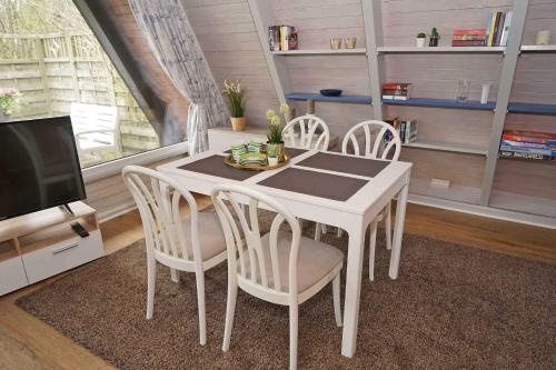 een witte eettafel met stoelen en een tv bij Zeltdachhaus _ Renovierung 2019 _ in Damp