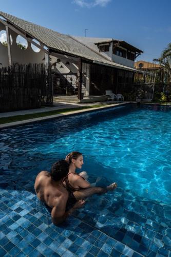 a man and woman sitting in a swimming pool at Reserva do Paiva suites in Cabo de Santo Agostinho