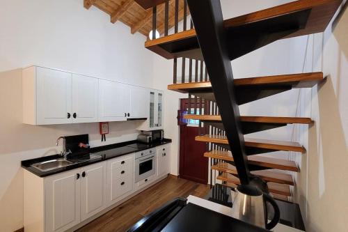 a kitchen with white cabinets and a spiral staircase at Casa 3 Meadas in Póvoa e Meadas