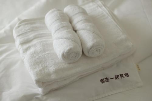 two rolls of white towels sitting on a bed at Peng Together B&B in Magong