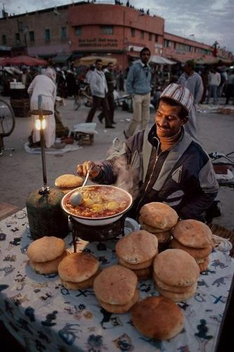 un hombre está cocinando comida en una mesa con galletas en Rayan Tours, en Fkih Ben Salah