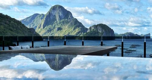 a reflection of a mountain in a body of water at H Hotel El Nido - Vegan Friendly Hotel Managed by H Hospitality Group in El Nido