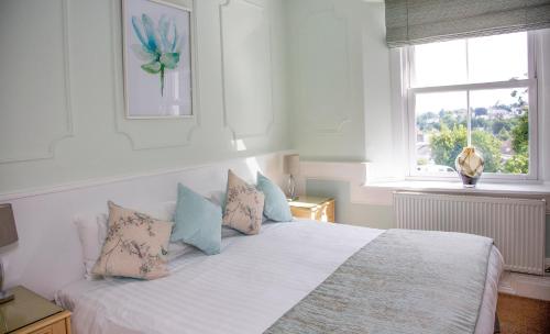 a bedroom with a white bed with pillows and a window at Carlton Court in Torquay