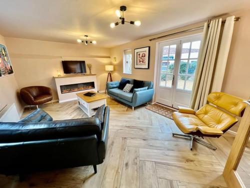 a living room with leather furniture and a fireplace at Penny Black Cottage in Lavenham