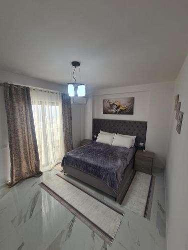 um quarto com uma cama e uma grande janela em Elite1 5C em Saranda