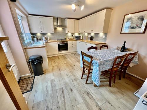 a kitchen with a table and chairs in a room at Penny Black Cottage in Lavenham