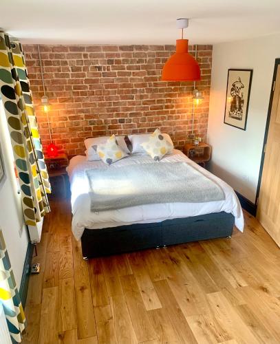 a bedroom with a bed and a brick wall at Station Masters Cottage in Hope