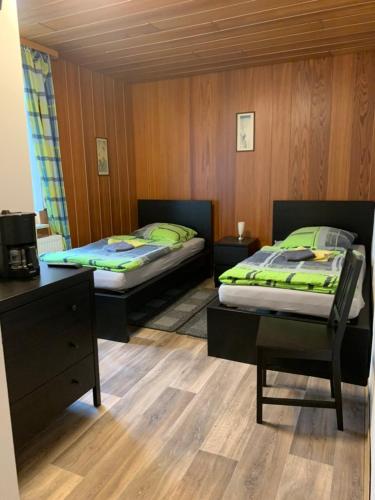 two beds in a room with wooden walls and wooden floors at Monteurzimmer Ahnetal Zweibettzimmer Einzelzimmer mit eigenem Bad in Dörnberg