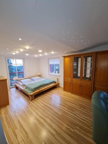 1 dormitorio con 1 cama, suelo de madera y ventanas en Haus Fernblick, en Kurort Bärenburg