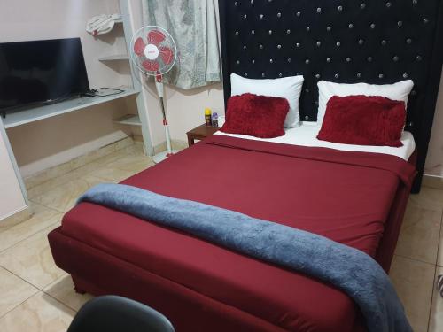 a bedroom with a red bed with red pillows and a fan at House of Joy in Lilongwe