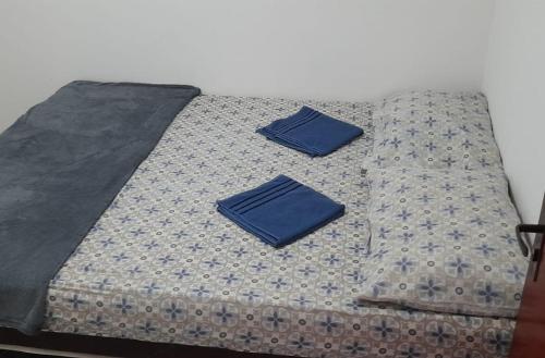 Una cama con dos almohadas azules encima. en Apto Araujo Macae en Macaé