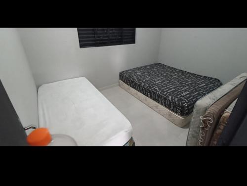 een kleine slaapkamer met een bed en een stoel bij 200m da Praia, Piscina Itanhaém in Itanhaém