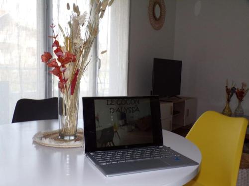a laptop computer sitting on a table with a vase at Bienvenue au Cocon d'Alyssa in Langon