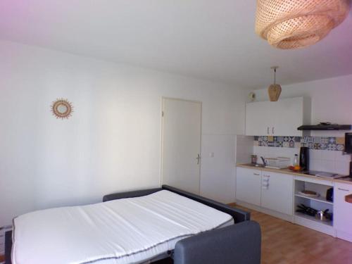 a bedroom with a white bed and a kitchen at Bienvenue au Cocon d'Alyssa in Langon