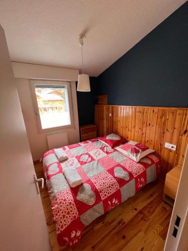 1 dormitorio con 1 cama con edredón rojo y blanco en Appartement vue panoramique terrasse parking internet gratuit - linge non fournis, en Font-Romeu-Odeillo-Via