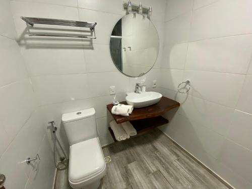 y baño con aseo, lavabo y espejo. en Piriápolis Hostel & suites, en Piriápolis