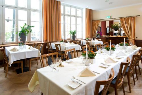 a restaurant with white tables and chairs and windows at martas Hotel Albrechtshof Berlin in Berlin