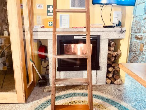 a ladder in a living room with a fireplace at Moinho de Brião in Montalegre