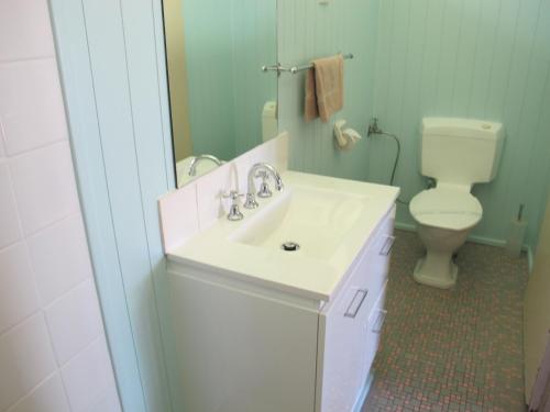 a white toilet sitting next to a sink in a bathroom at Merimbula Gardens Motel in Merimbula