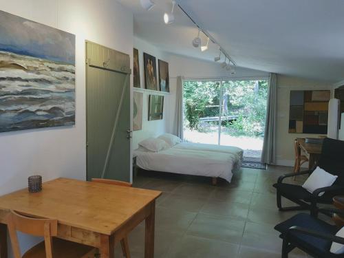 1 dormitorio con cama, mesa y ventana en Beautiful studio surrounded by nature en Lanet