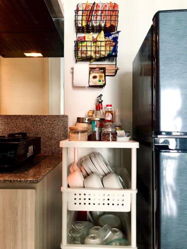 a kitchen with a refrigerator and a shelf with food at Benson Tower Surabaya Apartment 2BR by Le Ciel Hospitality in Lontar