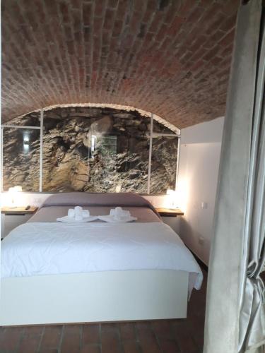 a bedroom with a white bed with a stone wall at Olimpo Affittacamere in Manarola