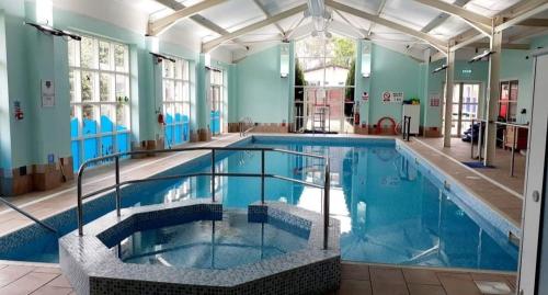 een groot zwembad met blauw water in een gebouw bij The Gull & Puffin Cresswell in Cresswell