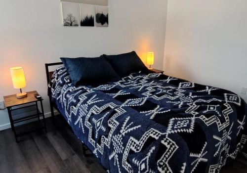 - une chambre dotée d'un lit avec une couverture bleue et blanche dans l'établissement Les Chalets Double K # 2, à Saint-Alexis-des-Monts